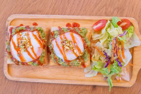 Bread, avocado sauce, bacon, spinach, egg benedict on the white plate and old Stock Photos
