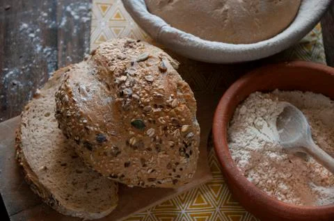 Bread baking, flour in ceramic bawl with wooden spoon, bread with seeds, sour Stock Photos