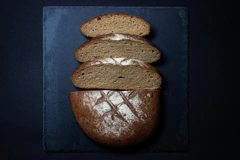 Bread on a black background. Sliced fresh homemade bread in a dark dish. Stock Photos