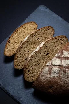 Bread on a black background. Sliced fresh homemade bread in a dark dish. Stock Photos