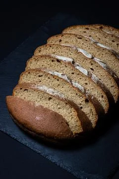 Bread on a black background. Sliced fresh homemade bread in a dark dish. Stock Photos