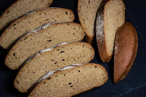 Bread on a black background. Sliced fresh homemade bread in a dark dish. Stock Photos