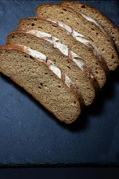 Bread on a black background. Sliced fresh homemade bread in a dark dish. Stock Photos