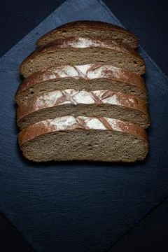 Bread on a black background. Sliced fresh homemade bread in a dark dish. Stock Photos