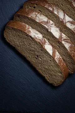 Bread on a black background. Sliced fresh homemade bread in a dark dish. Stock Photos
