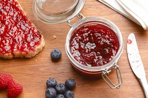 Bread with blueberry and raspberry jam on wooden table top view Stock Photos