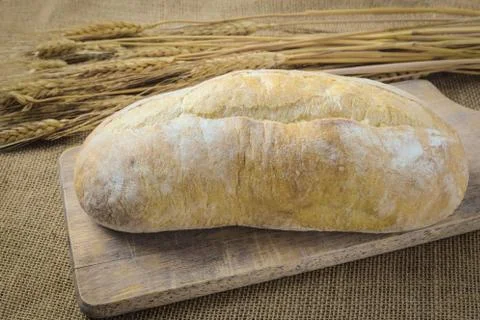 Bread on bread board with wheat on burlap background Stock Photos