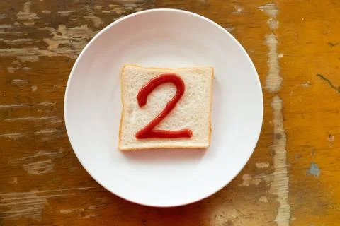 Bread of breakfast is written 2 by ketchup on write plate. A to Z and Number  Stock Photos