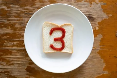 Bread of breakfast is written number 3 by ketchup on write plate. A to Z and  Stock Photos