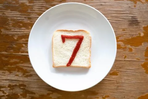 Bread of breakfast is written number 7 by ketchup on write plate. A to Z and  Stock Photos