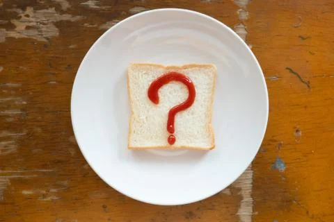 Bread of breakfast is written Question mark sign by ketchup on write plate. A Stock Photos
