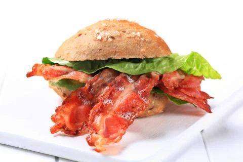 Bread bun with strips of crispy bacon Stock Photos