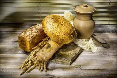 Bread, bun, wheat, clay jug on wooden background Stock Photos