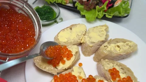 Bread with butter and red caviar. red caviar being placed on buttered multigrain Stock Footage 316947819