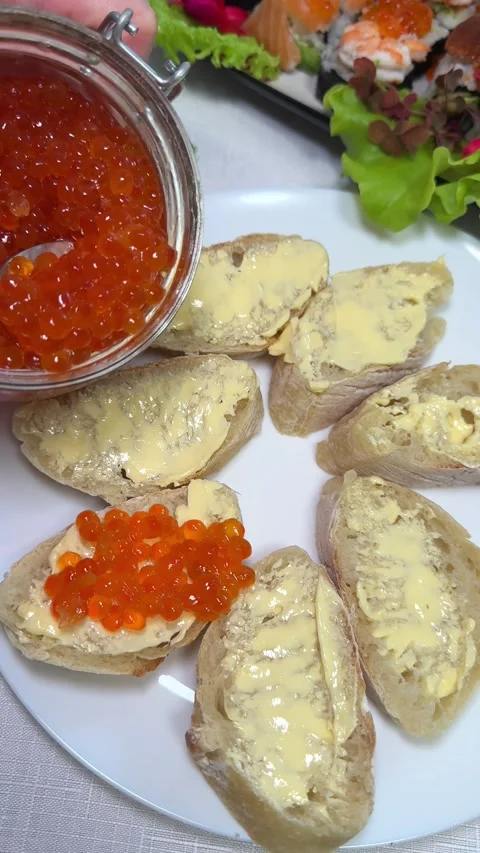 Bread with butter and red caviar. red caviar being placed on buttered multigrain Stock Footage 317723331