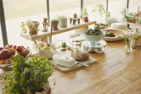 Bread, butter, fruit, pasta,asparagus and fresh herbs on dining room table Stock Photos