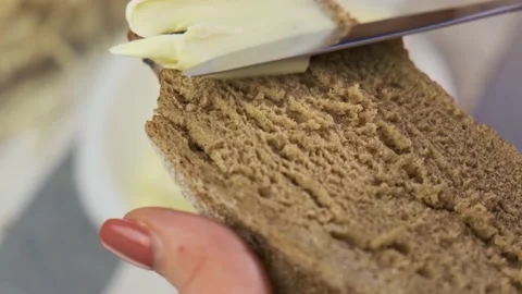 Bread with butter. Knife smearing soft butter on slice of bread, closeup view Stock Footage 156237331