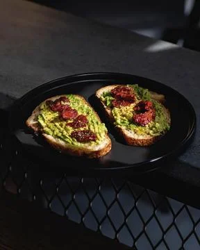Bread with chipotle guacamole, on a black ceramic plate Stock Photos