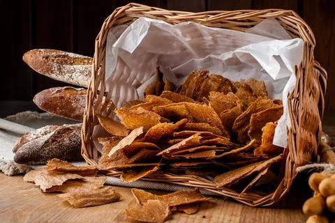 Bread chips. Basket with chips. Scattered crispy pastries. Chips in a wooden Stock Photos