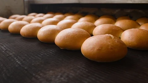Bread comes out of the oven in close-up on a conveyor belt and is sprayed with Video stock 124253099