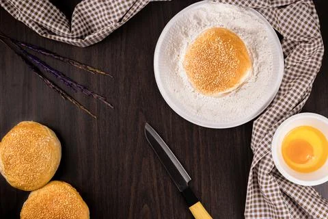 Bread concept buns, a dish of flour, a knife, and a tiny bowl of raw egg lyin Stock Photos