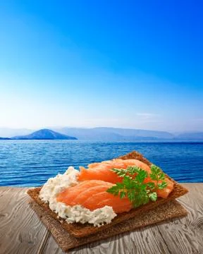 Bread crisp with salmon, rustic table, seascape 스톡 사진