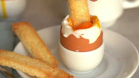 Bread crouton dips in soft-boiled egg in egg cup. Breakfast. Food background Stock Footage 293229493