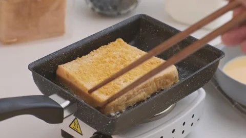 Bread croutons in an egg are fried in a pan. Close-up. Fried bread slices Stock Footage 242565539