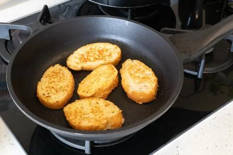 Bread croutons in an egg are fried in a pan. Close-up. Top-side view Stock Photos