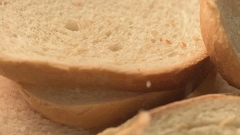 Bread crumbs falling on slices of white bread in slow motion on spinning plat Vídeos de archivo 164762105