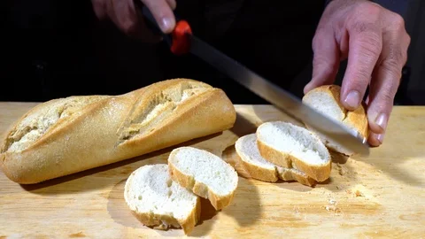 Bread cut by chef's hands on wooden cutting board. Vidéo 125728201