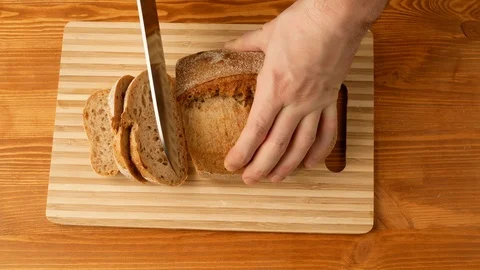 Bread is cut into pieces with a knife on the kitchen board. Stock Footage 108274757