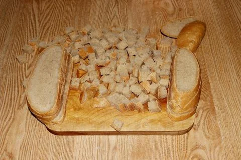 The bread is cut into small cubes on a cutting board. Stock Photos