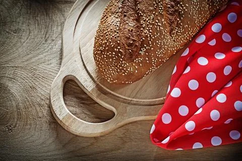 Bread cutting board red tablecloth on wooden background 库存照片
