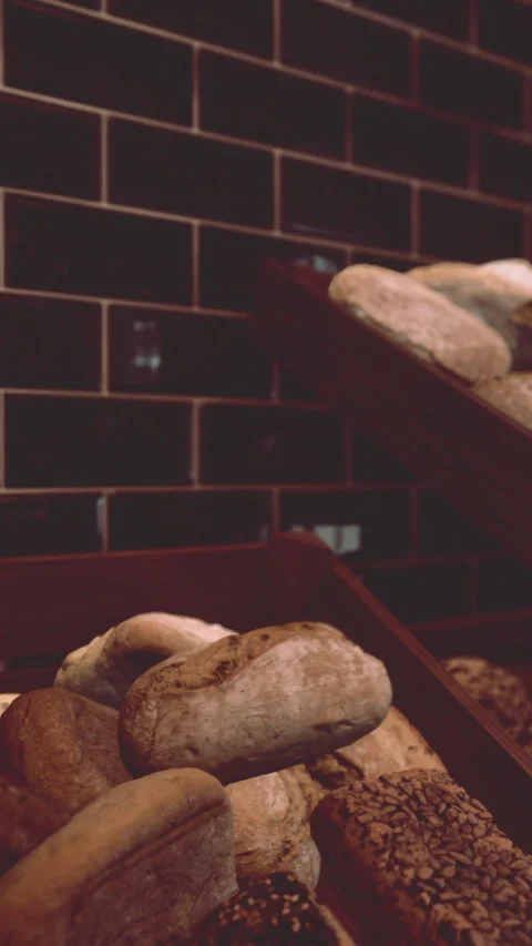 Bread displayed in wooden trays at bakery with dark tiles in the background Stock Footage 340638145