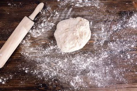 Bread dough next to a rolling pin on a wood table Stock Photos