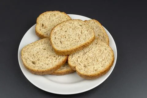 Bread dried in the oven on a white ceramic plate on a black background Stock Photos