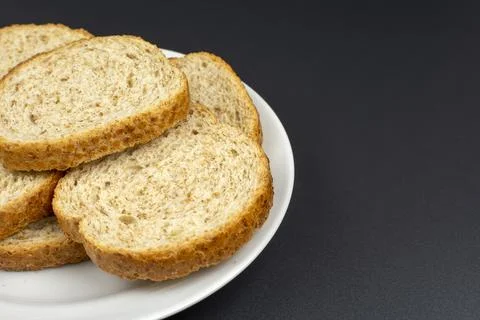 Bread dried in the oven on a white ceramic plate on a black background Stock Photos