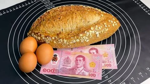 Bread, eggs and Thai baht on a black kitchen mat Fotos Stock