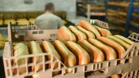 A bread factory worker or Baker moves fresh loaves, bread and pastries from a Stock-Footage 130719021