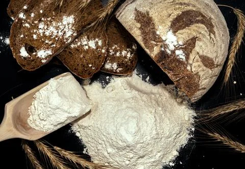 Bread, flour, spikelets of wheat on a black background. Flour Foto stock