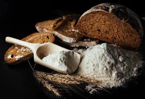 Bread, flour, spikelets of wheat on a black background. Flour Stock Photos