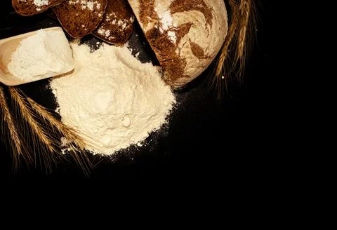 Bread, flour, spikelets of wheat on a black background. Flour Foto stock