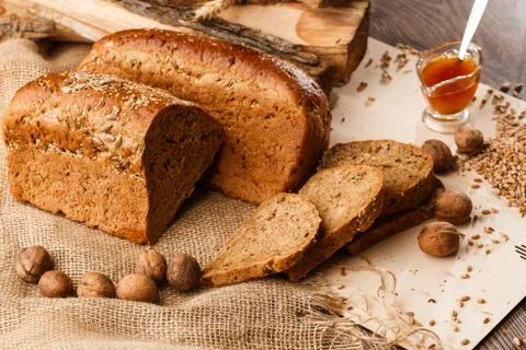 Bread in form of triangle and with nuts and honey near spikelets of wheat lie Stock Photos