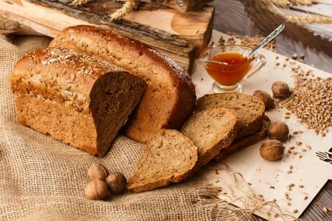 Bread in form of triangle and with nuts and honey near spikelets of wheat lie Stock Photos