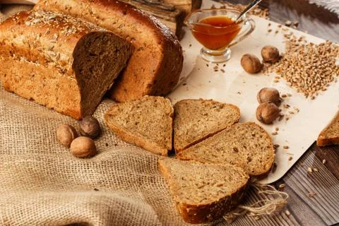 Bread in form of triangle and with nuts and honey near spikelets of wheat lie Stock Photos