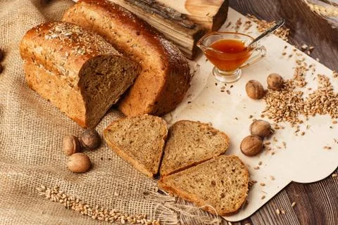 Bread in form of triangle and with nuts and honey near spikelets of wheat lie Stock Photos
