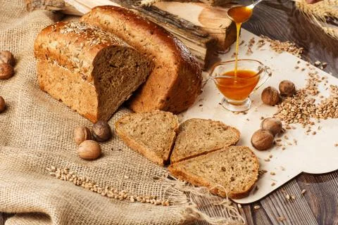 Bread in form of triangle and with nuts and honey near spikelets of wheat lie Stock Photos