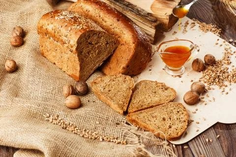 Bread in form of triangle and with nuts and honey near spikelets of wheat lie Stock Photos