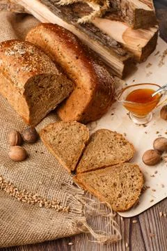 Bread in form of triangle and with nuts and honey near spikelets of wheat lie Stock Photos